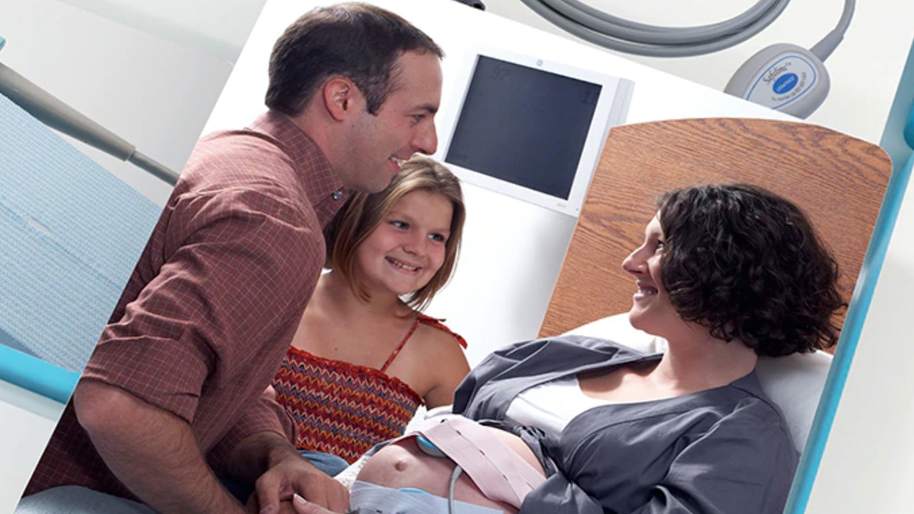 pregnant woman in a hospital bed with her husband and daughter next to her